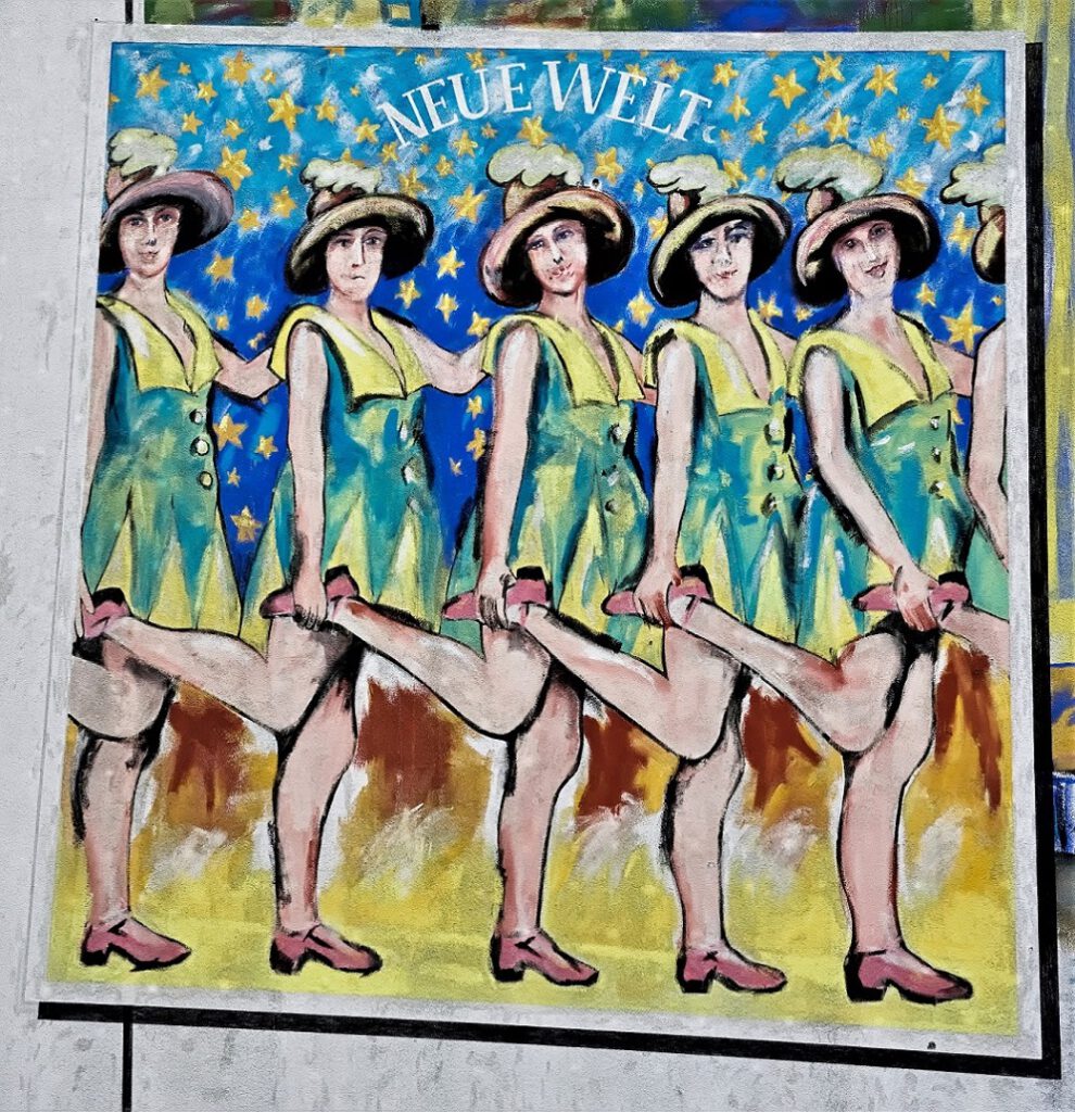 Von Pellkartoffeln mit Heringsschwanz / Giebelmalerei „Revuegirls in der Neuen Welt“ in der Donaustraße vom Parkdeck Lidl aus gesehen (12) (AR 01/2023)