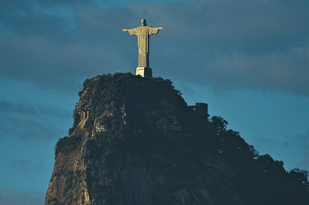 Der Cristo Redentor befindet sich auf dem Gipfel des Corcovado-Berges im Tijuca-Nationalpark in Rio de Janeiro. Der Park ist einer der größten städtischen Regenwälder der Welt und beheimatet den Atlantischen Regenwald. Die Christusstatue ist ein weltberühmtes Wahrzeichen, das auf einer Höhe von 709 Metern über dem Meeresspiegel thront. Der Regenwald bietet Wanderwege, Wasserfälle und eine reiche Flora und Fauna, und ist ein beliebtes Ziel für Naturliebhaber und Touristen. (AR 12/2019)