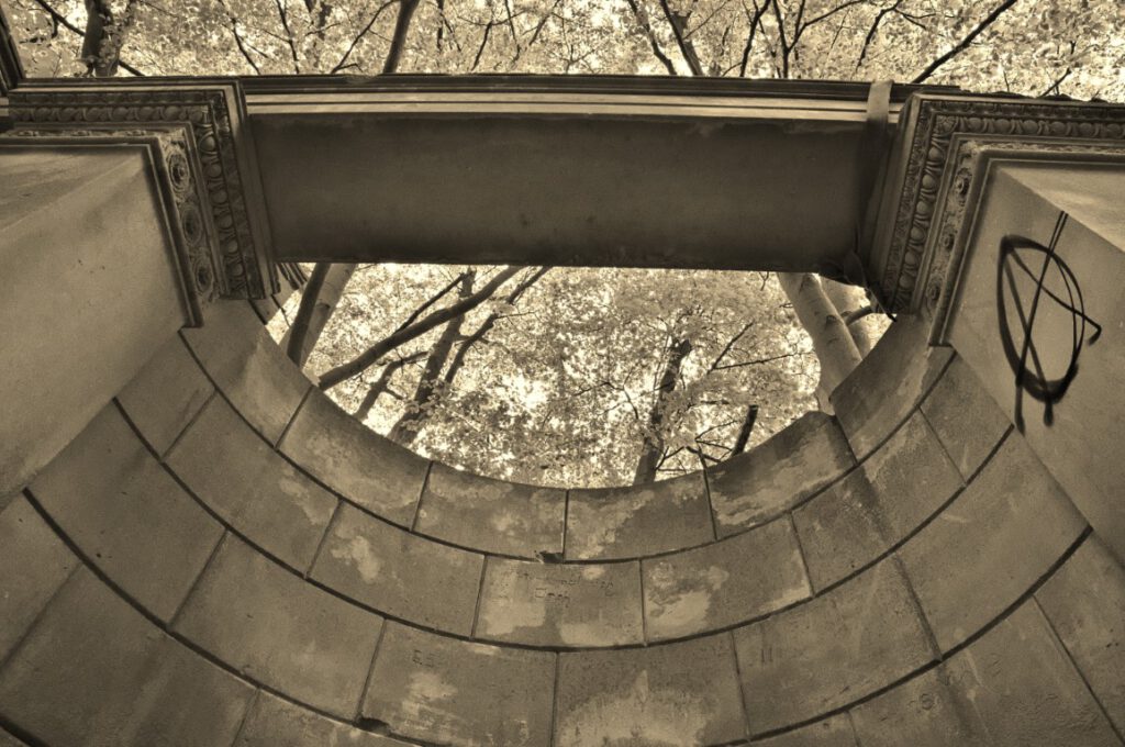 Blick durch den halbkreisförmigen Mauerring des Pavillons von Schloss Dwasieden hinauf in die Baumkronen