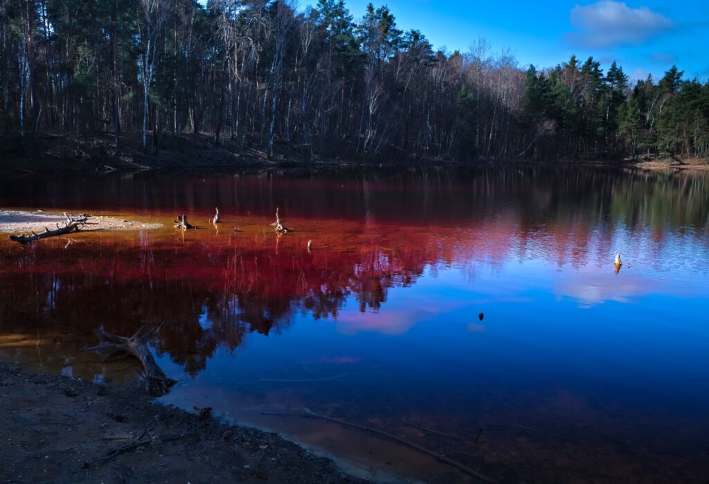 Rötlich gefärbtes Wasser eines Restlochs in ehemaligem Braunkohletagebau