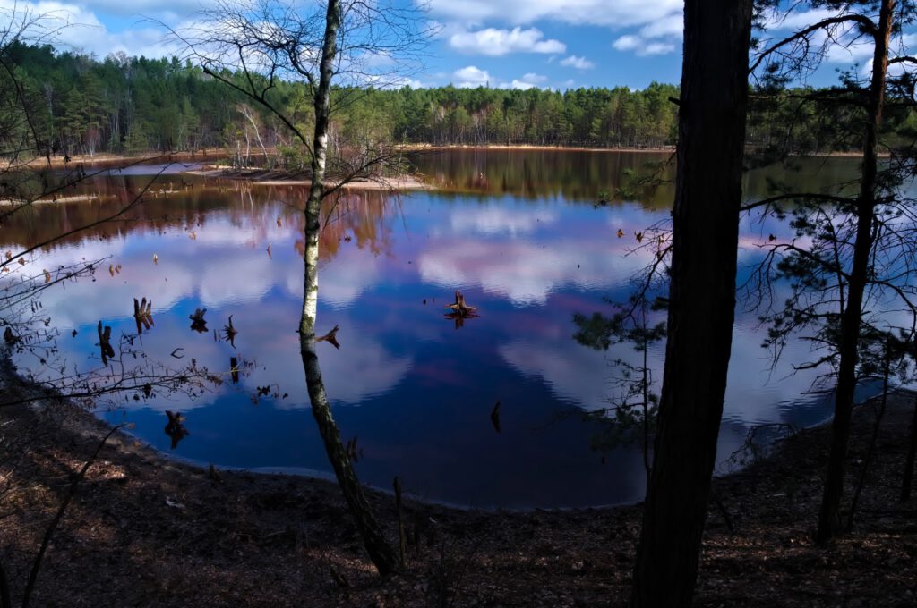 Rot gefärbter Tagebausee in der Lausitz mit ruhiger Wasseroberfläche