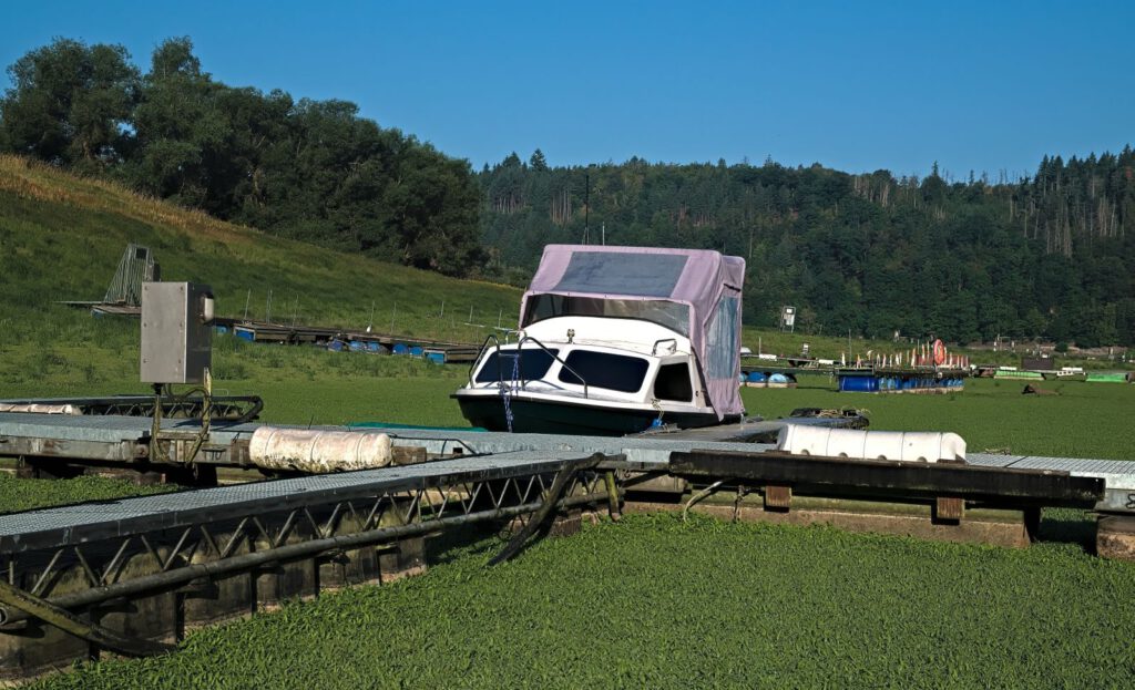Motorboot zwischen stillgelegten Stegen auf dem bewachsenen Grund des Edersees