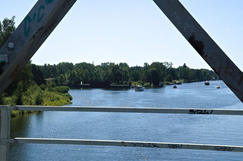 Blick von der Klinkerhafenbrücke durch das Stahlfachwerk auf den Oder-Havel-Kanal mit Booten.